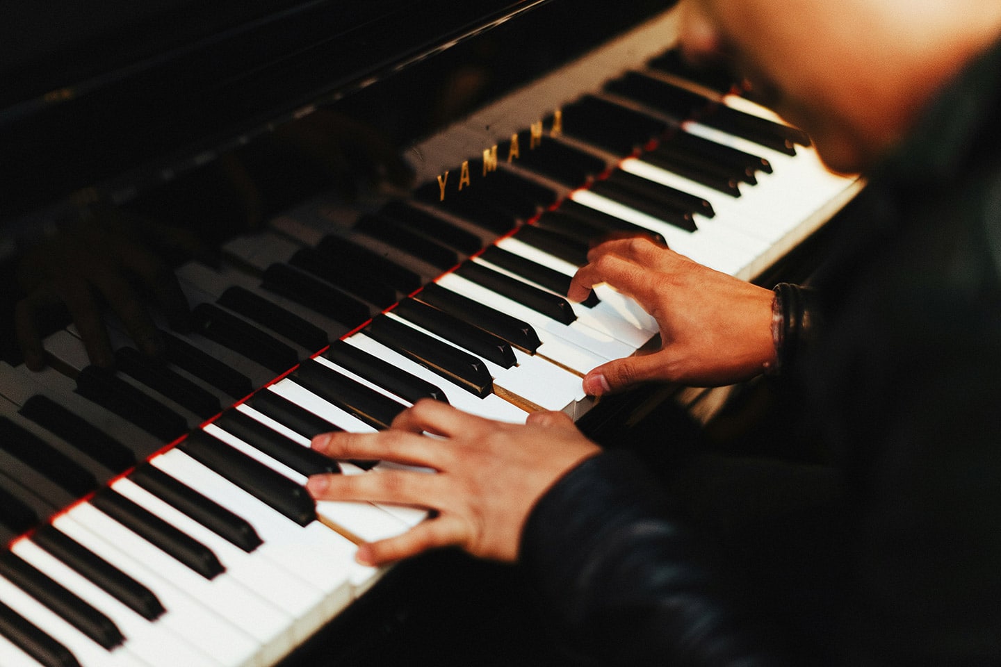 musician playing on a black yamaha piano