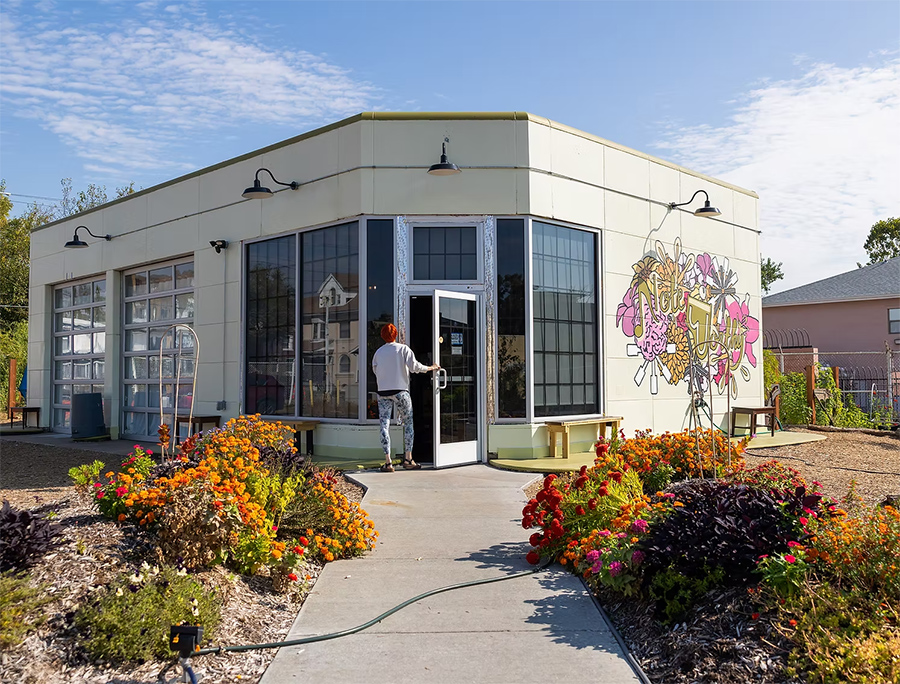 Front of the cafe with flowers along the path and art on the wall